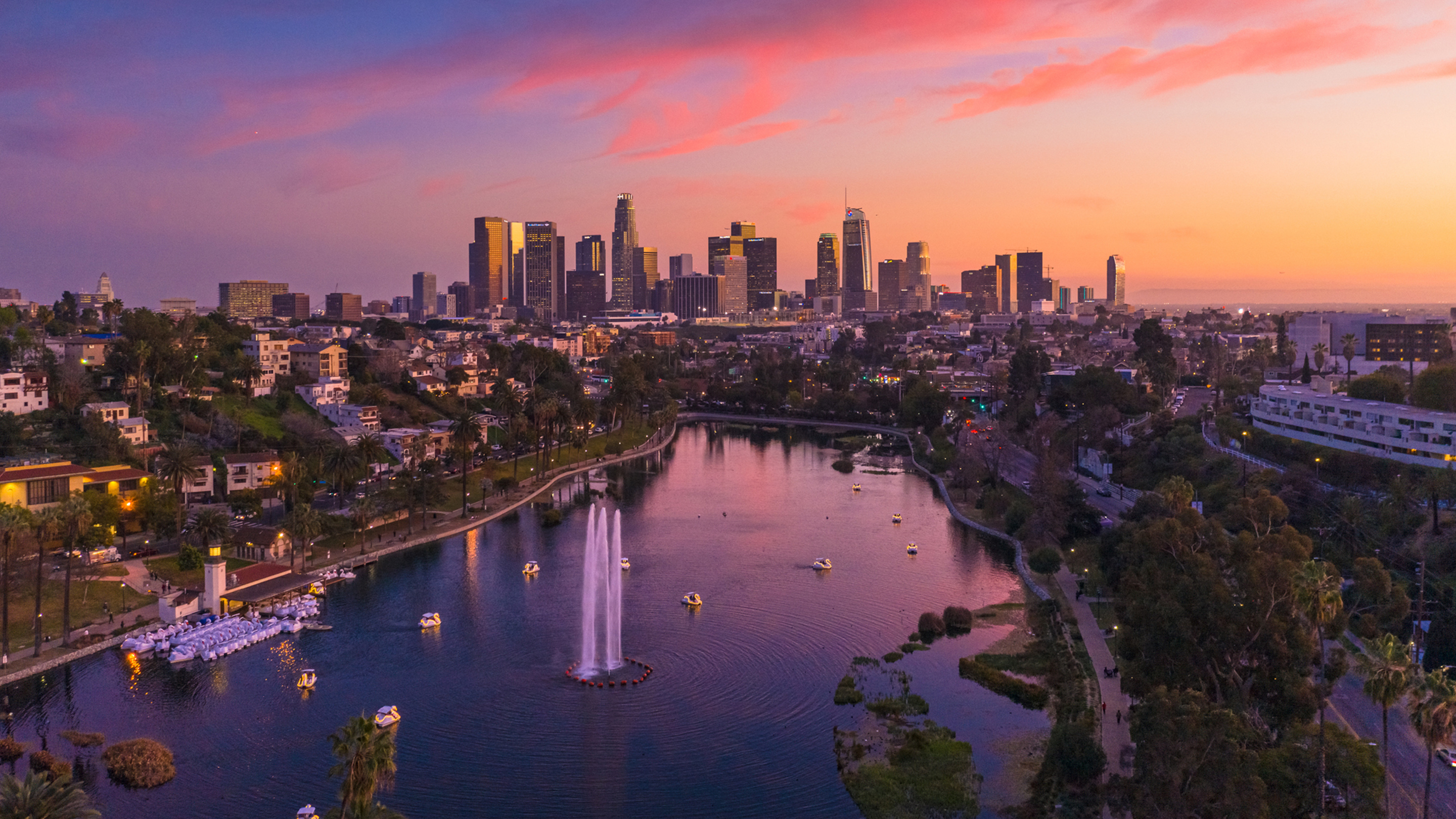 Luftaufnahme mit Blick auf die Wolkenkratzer von Los Angeles mit einem Park und See im Vordergrund.