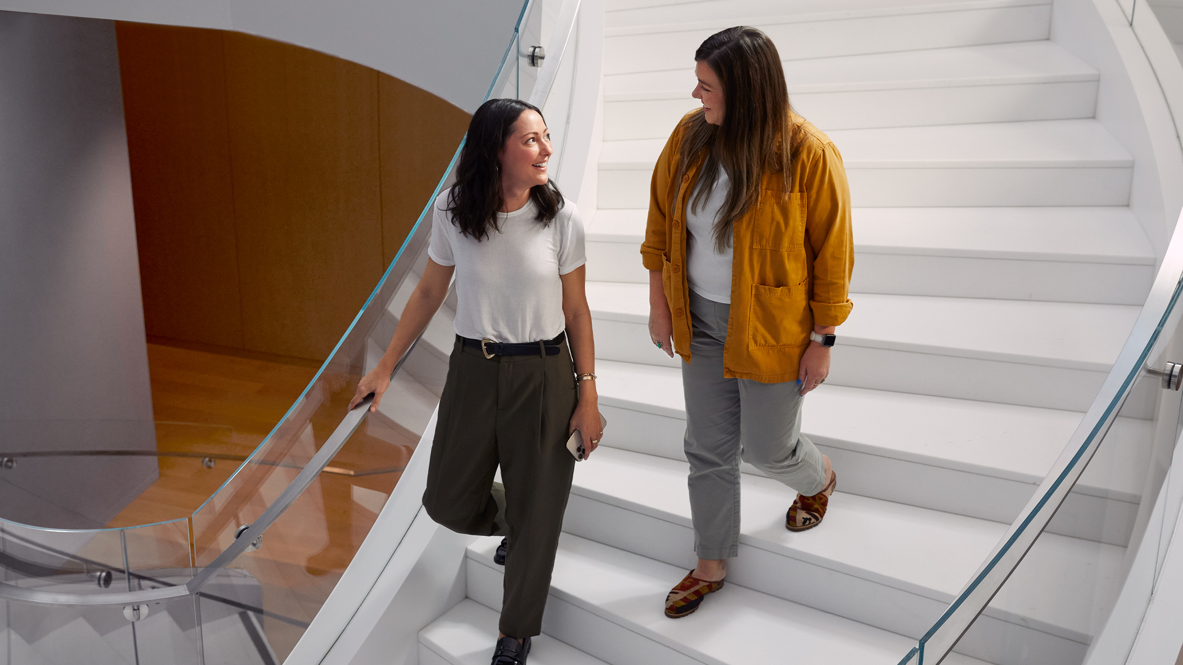 Zwei Apple Teammitglieder gehen eine breite, gewundene Treppe herunter. 