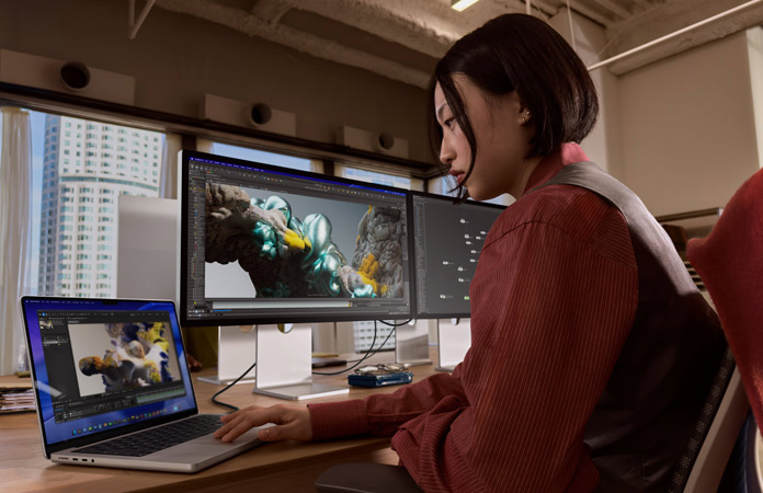 Henkilö työskentelee toimistossa MacBook Prolla, johon on liitetty Studio Display XDR
