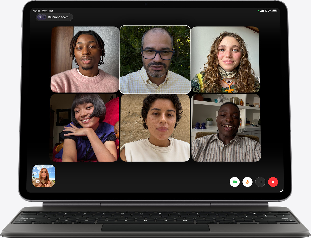 Un iPad Air nero visto di fronte con Magic Keyboard nera; il display mostra una chiamata FaceTime con più partecipanti