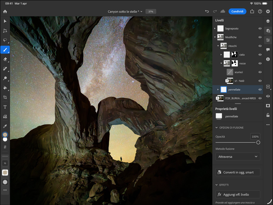 Un iPad Pro nero siderale in orizzontale visto di fronte, angoli arrotondati, cornice del display nera, il display mostra la foto di un canyon e un cielo stellato che viene modificata, a destra i livelli di modifica, gli strumenti e gli effetti tra cui pennelli, regolazioni e altri