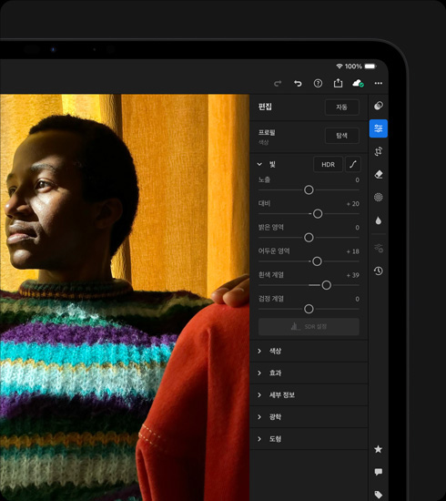 가로 방향으로 놓인 스페이스 블랙 색상 iPad Pro의 앞면 외관. 화면에는 컬러풀한 스웨터를 입고 있는 사람을 촬영한 사진을 편집 중인 보이고, 오른쪽 화면에는 도구 및 효과 메뉴가 열려 있습니다.