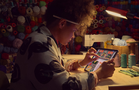 شخص يجلس خلف مكتب ويستخدم إصبعين على شاشة iPad لتكبير صورة.