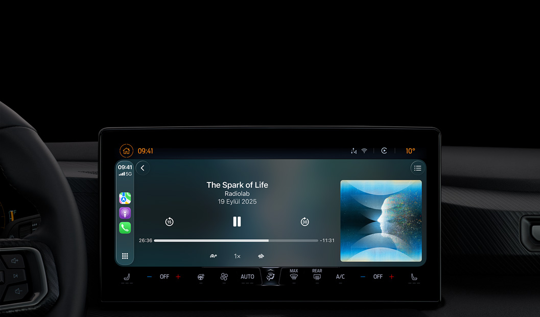 Bir arabanın iç görünümü, orta konsol ekranında CarPlay aracılığıyla Apple Podcast’ler uygulaması açık, Radiolab’in “The Spark of Life” podcast’i oynatılıyor, oynatma denetimlerinde geriye atla, duraklat ve ileriye atla yer alıyor.