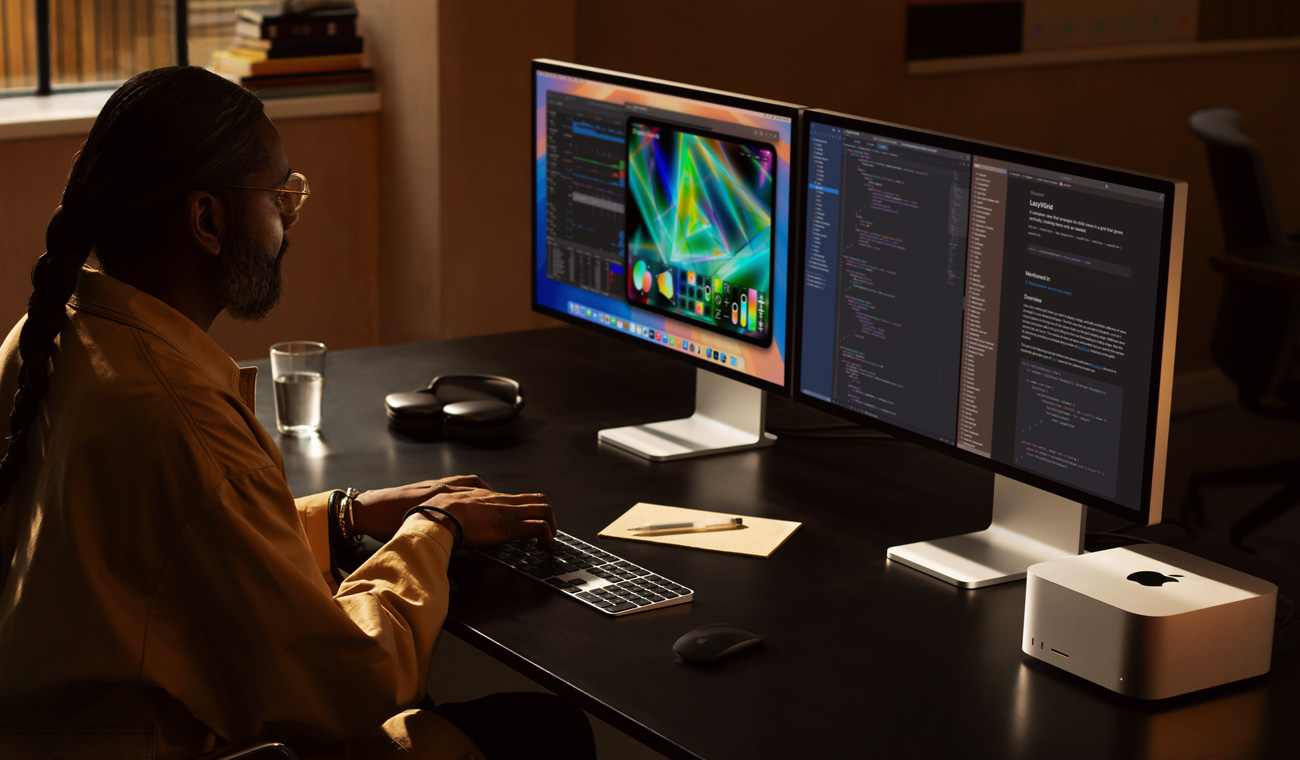 一位專業人士正以 Mac Studio 和兩部 Studio Display 顯示器工作