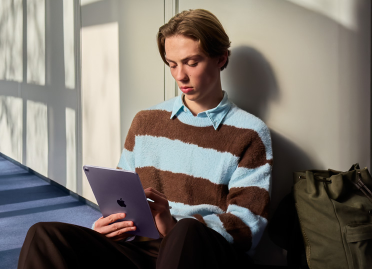 A person sitting on the floor in a light-filled room, using iPad and Apple Pencil.