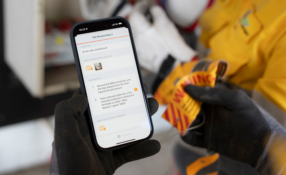 Zwei Hände halten ein iPhone, das auf dem Bildschirm die Anweisung «13C Process Step 3» zur Durchführung eines Schalttafeltests anzeigt