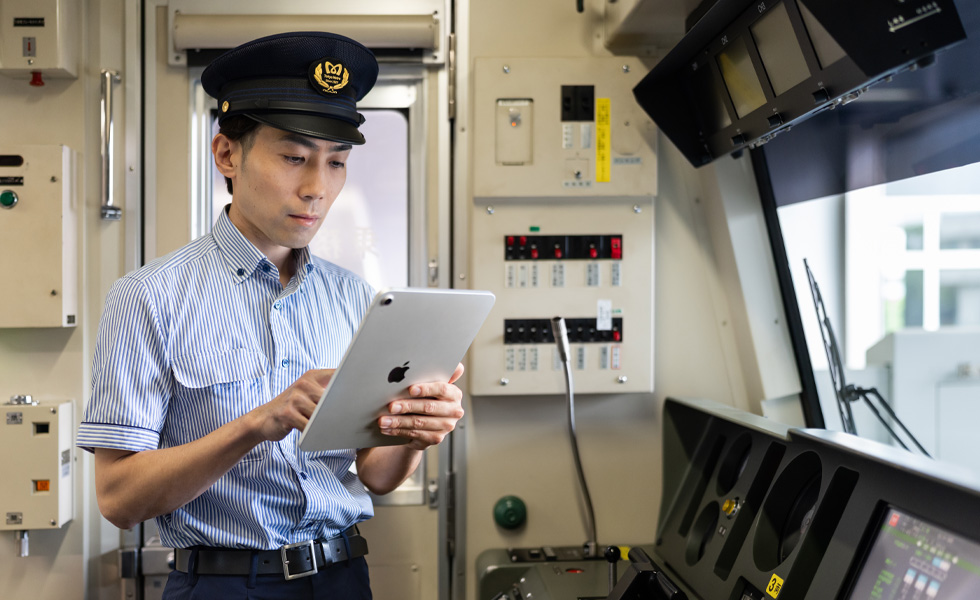 Ein Lokführer interagiert mit einem iPad, während er in der hellen Fahrkabine des Zuges steht, den er steuert.