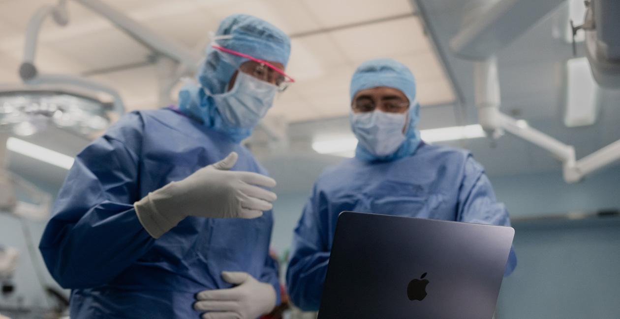 Twee chirurgen bespreken iets op het scherm van een MacBook Pro in de OK.